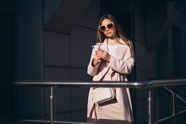 Mujer en abrigo caminando en la calle y hablando por teléfono