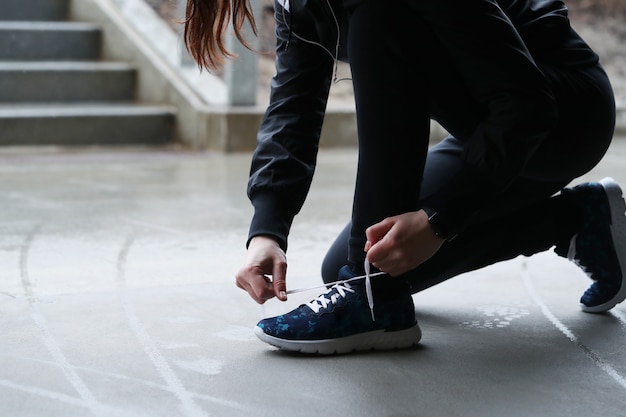 Una mujer se abrocha los cordones de los zapatos. Persona atando cordones de los zapatos.