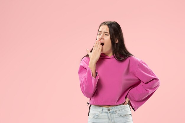 Mujer aburrida. Concepto aburrido, aburrido y tedioso. Joven mujer emocional bastante caucásica. Las emociones humanas, el concepto de expresión facial. Aislado en la pared rosa de moda