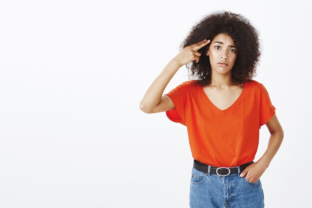 Mujer aburrida con peinado afro posando en el estudio