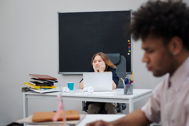 Foto gratuita mujer aburrida sentada en el escritorio