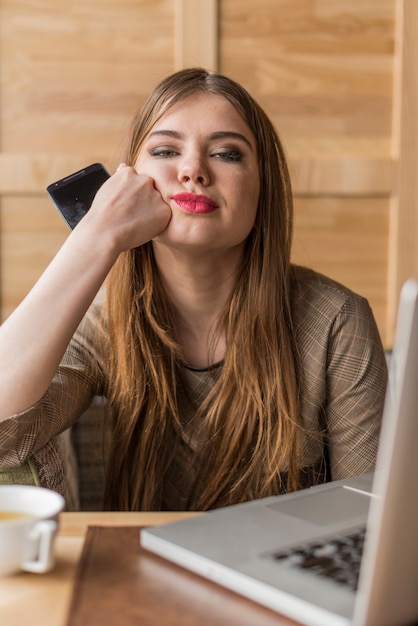 Foto gratuita mujer aburrida con teléfono móvil en la mano