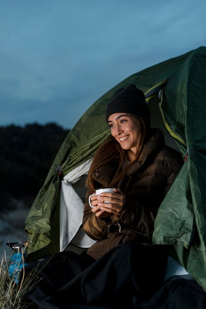 Mujer acampando y sosteniendo una taza de té