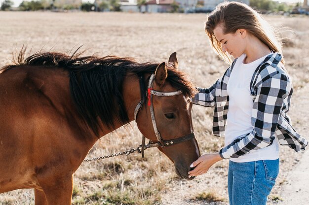 Mujer acariciando adorable caballo