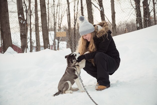 Mujer acariciando a joven perro siberiano