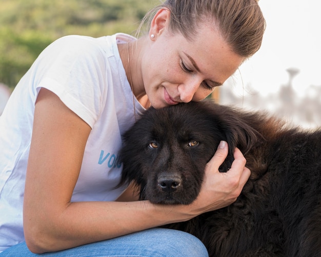 Foto gratuita mujer acariciando a un perro negro esponjoso al aire libre