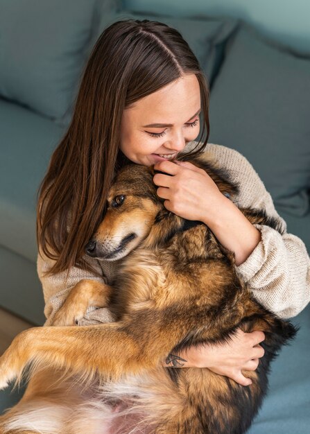 Mujer acariciando a su lindo perro en casa durante la pandemia