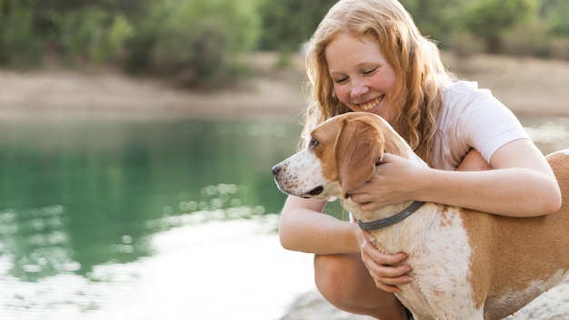 Mujer acariciando a su perro junto al lago