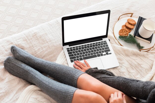 Mujer acogedora en la cama con laptop y snack