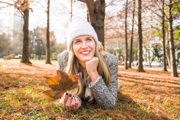 Mujer acostada en el bosque de otoño y sonriendo