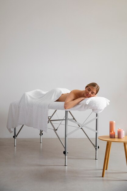 Mujer acostada en la cama de masaje lista para la sesión