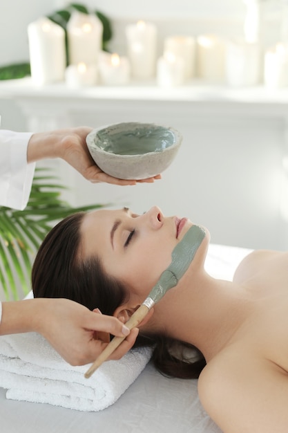 Mujer acostada recibiendo un tratamiento de belleza facial.