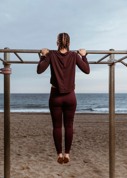 Mujer activa haciendo ejercicios de fitness en la playa al aire libre