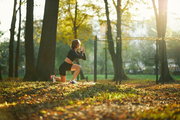 Mujer activa en ropa deportiva haciendo sentadillas en el parque