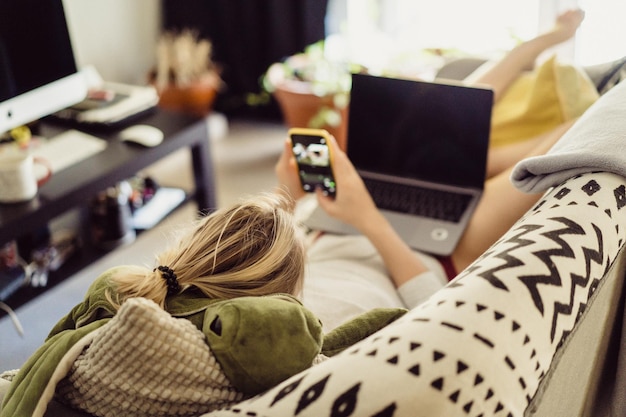 la mujer se acuesta en un sofá con una computadora portátil. Ocio en aislamiento. Trabajando en una computadora portátil desde casa.