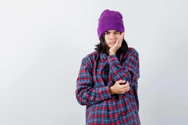 Mujer adolescente apoyando la barbilla en el gorro de palma mirando aburrido