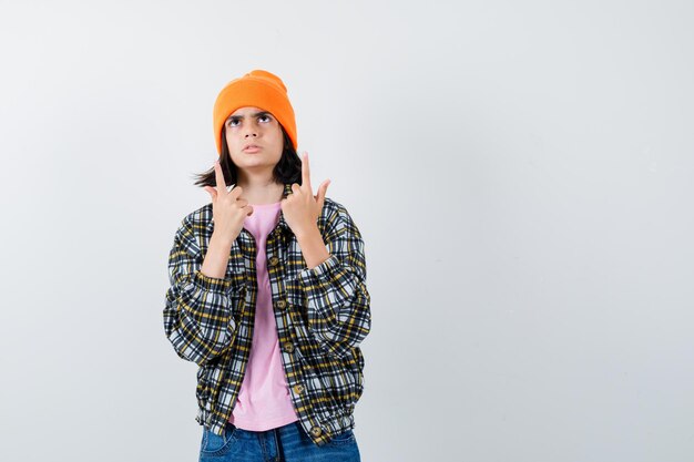 Foto gratuita mujer adolescente en camisa a cuadros y gorro gesticulando aislado