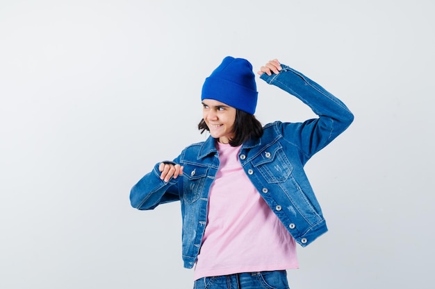 Mujer adolescente en camiseta rosa chaqueta de jean y gorro mostrando gesto ganador