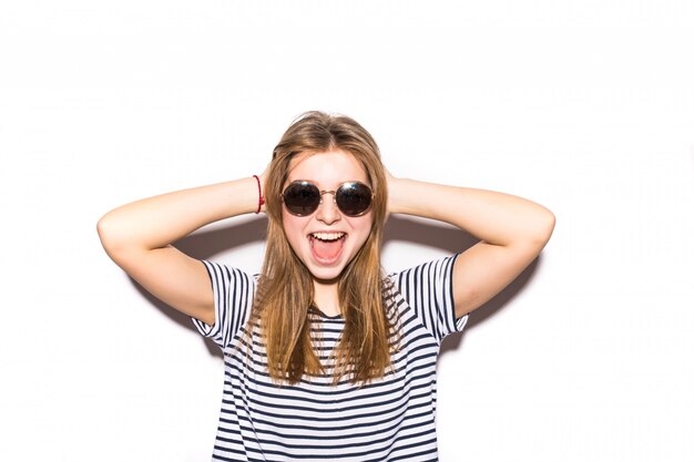 Mujer adolescente casual divertida con gafas de sol de moda gesticular aislado en una pared blanca