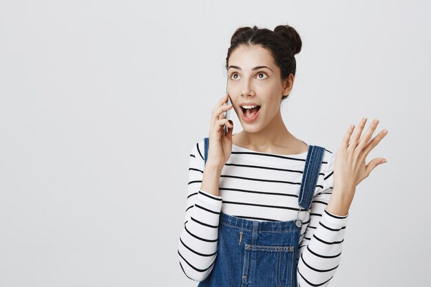 Mujer adolescente despreocupada hablando por teléfono, gesticulando