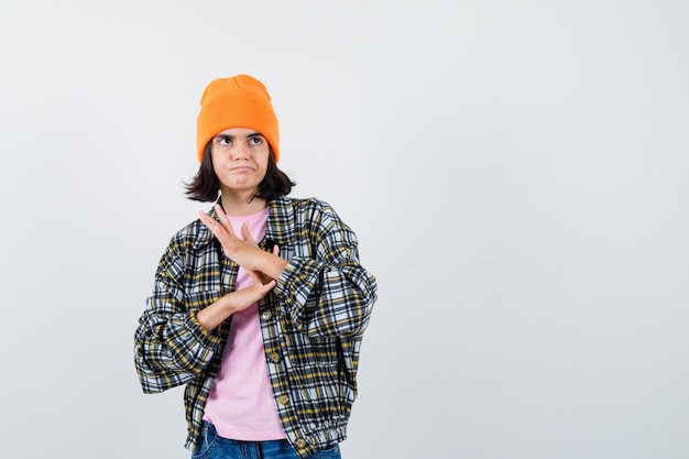 Mujer adolescente frotando sus palmas juntas en camiseta chaqueta beanie mirando pensativo