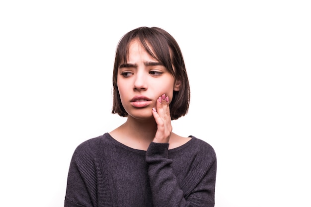 Mujer adolescente presionando su mejilla amoratada con una expresión dolorosa como si tuviera un terrible dolor de muelas.