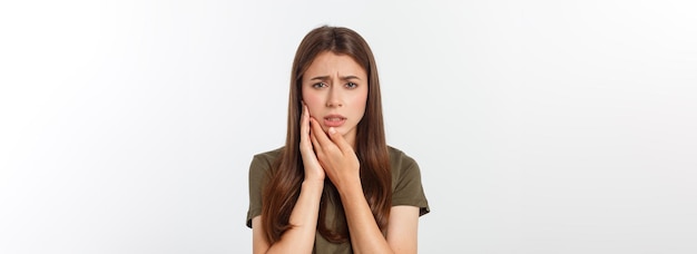 Mujer adolescente presionando su mejilla magullada con una expresión dolorosa como si tuviera un diente terrible