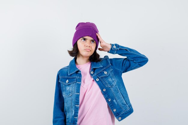 Mujer adolescente sosteniendo la mano en la cabeza en camiseta chaqueta beanie mirando pensativo