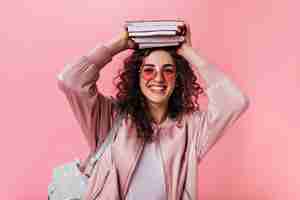 Foto gratuita mujer adolescente en traje rosa posando con libros