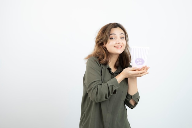 Mujer adorable joven sosteniendo una caja de palomitas de maíz y posando. foto de alta calidad