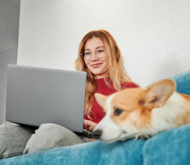 Mujer con adorable mascota trabajando o estudiando en una laptop en casa