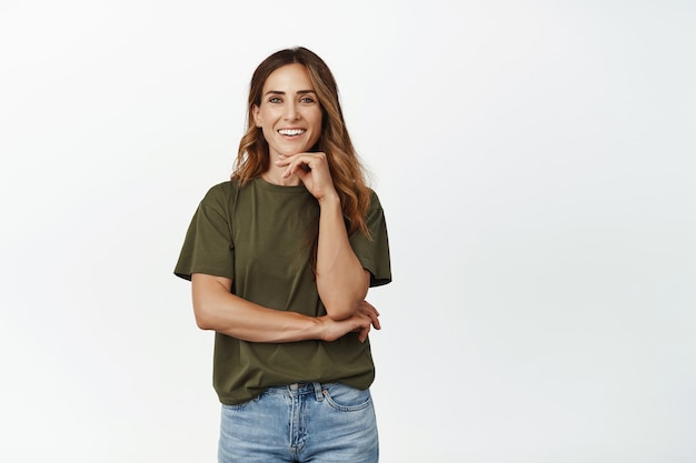 Mujer adulta ambiciosa sonriendo feliz, mirando hacia adelante con confianza, de pie en pose casual segura de sí misma.