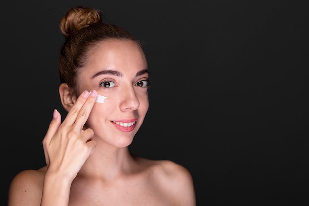 Mujer adulta aplicando producto para el cuidado de la piel