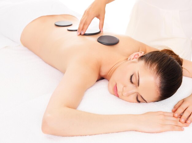 Mujer adulta con masaje con piedras calientes en el salón de spa. Concepto de tratamiento de belleza.