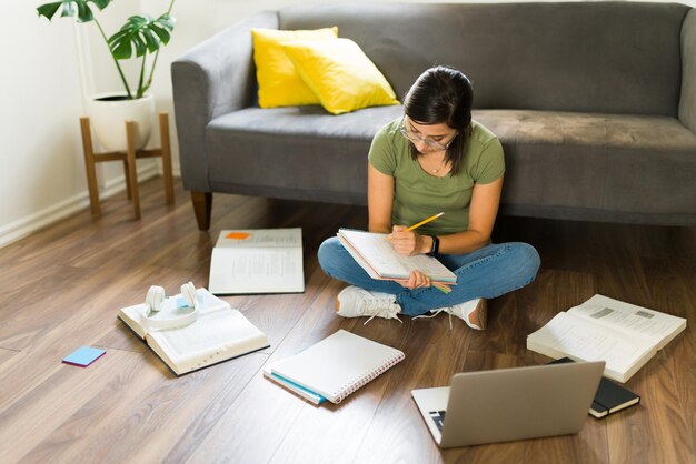 Mujer adulta media haciendo su tarea universitaria en casa y estudiando con libros para exámenes universitarios
