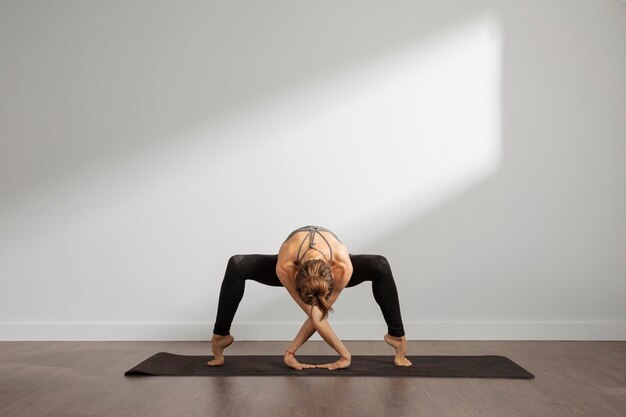 Mujer adulta practicando yoga en casa