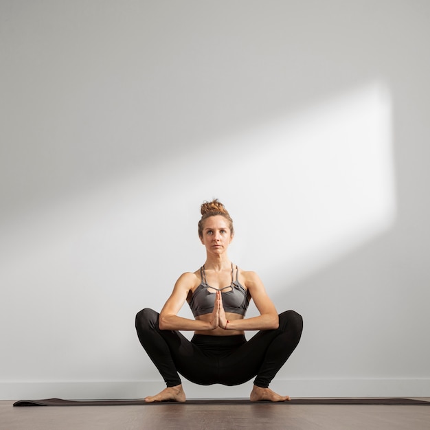 Mujer adulta practicando yoga en casa