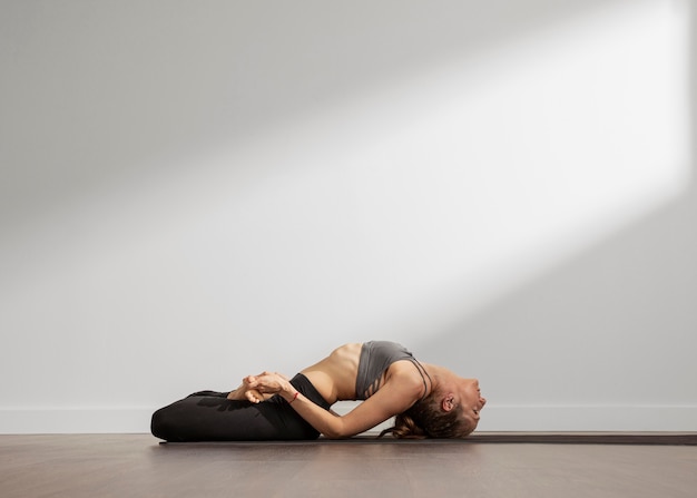 Mujer adulta practicando yoga en casa