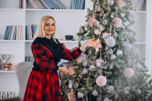 Mujer adulta que adorna el árbol de navidad