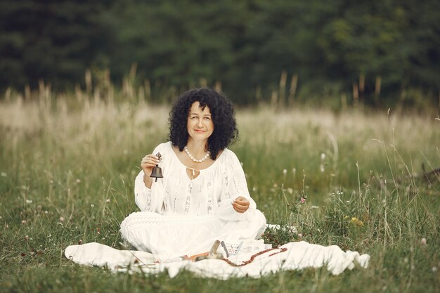 Mujer adulta que muestra la herramienta de meditación en la pradera