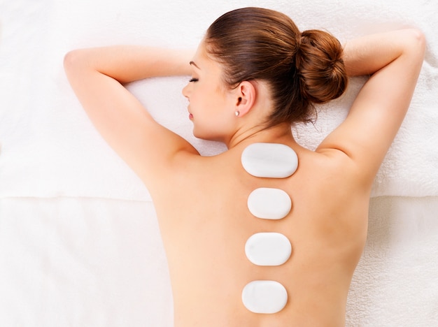 Foto gratuita mujer adulta relajante en el salón de spa con terapia con piedras calientes en la columna vertebral