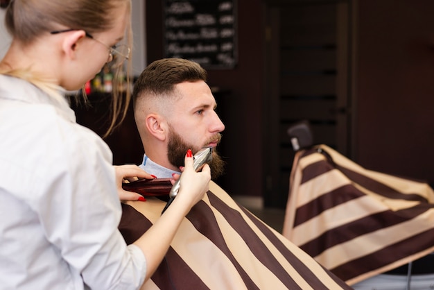 Mujer afeitarse la barba de su cliente con espacio de copia