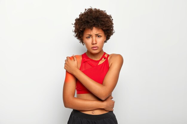 Mujer afligida llora de un dolor terrible, toca cuchillas rojas, vestida con ropa casual, muestra los hombros desnudos