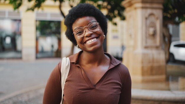 Mujer africana alegre con gafas mirando feliz sonriendo a la cámara