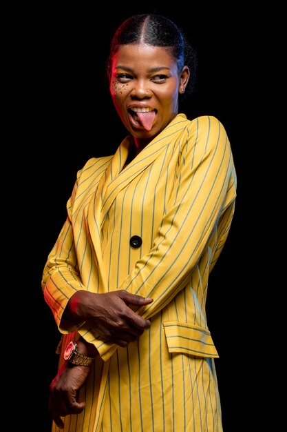 Mujer africana en chaqueta amarilla con su lengua fuera