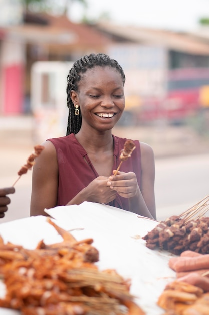Mujer africana comiendo comida en la calle