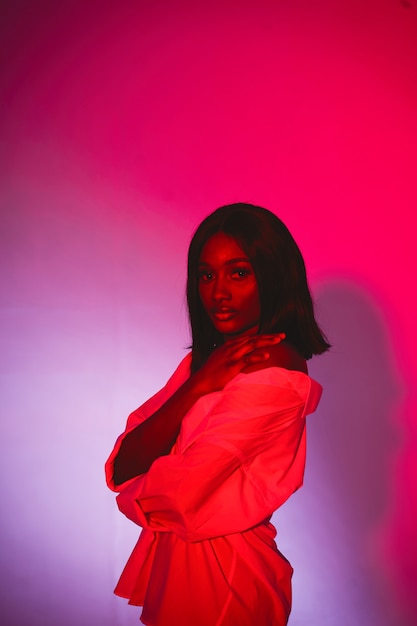 Mujer africana en un estudio. Pared roja. Mujer con camisa blanca.