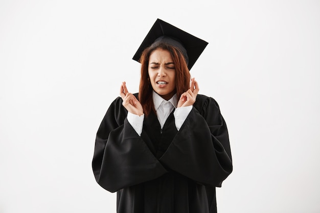 Mujer africana graduada en manto negro rezando. Copia espacio