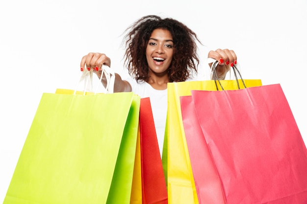 Mujer africana joven feliz que sostiene bolsos de compras.