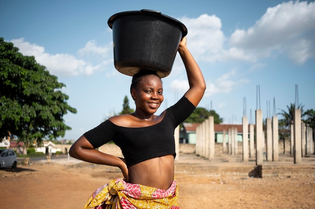 Mujer africana, teniendo, un, balde de agua, en, ella, cabeza
